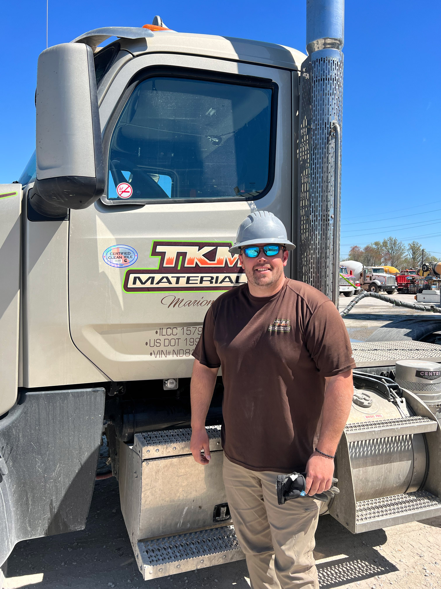 tkm materials truck driver standing by vehicle at job site