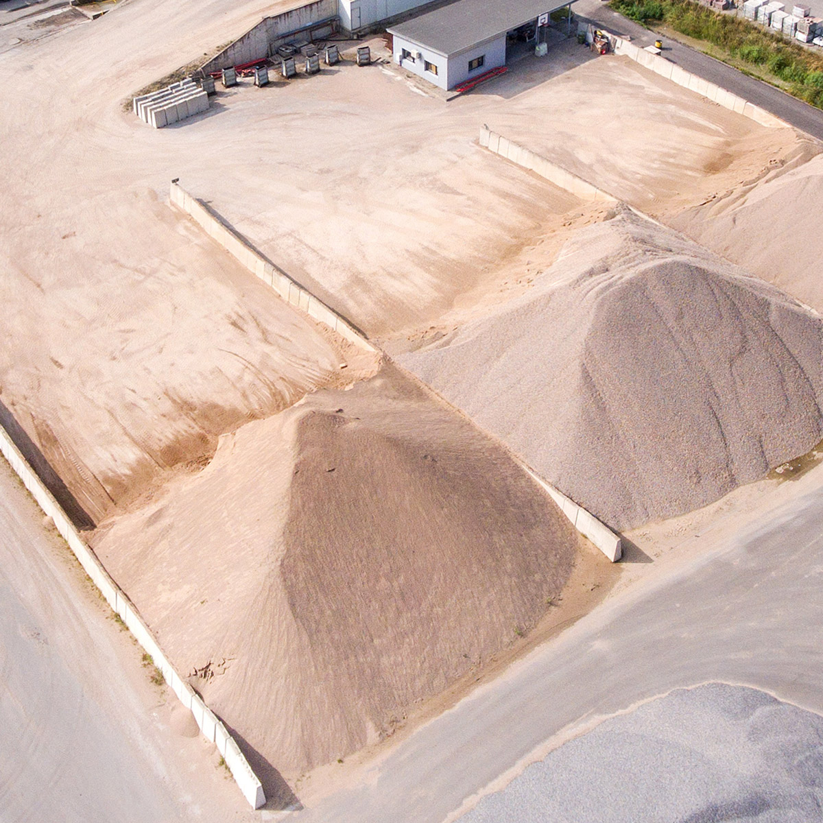 three large piles of sand at factory to be delivered by tkm materials