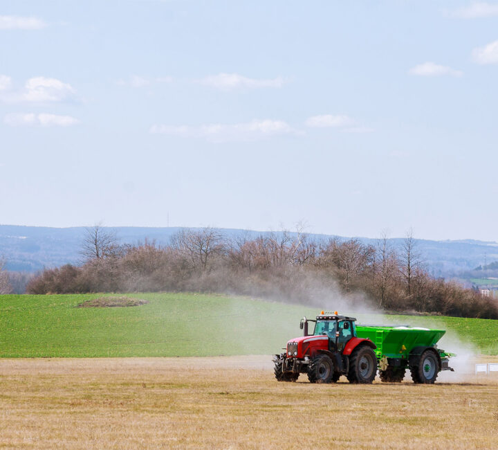 tractor spreading fertilizer delivered by tkm materials on to field