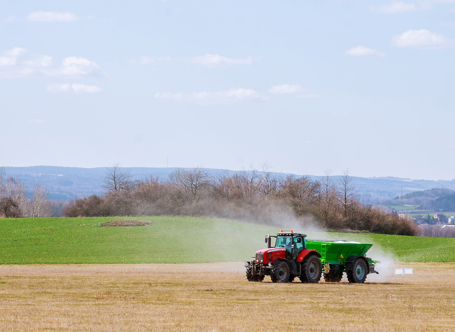 tractor spreading fertilizer delivered by tkm materials on to field