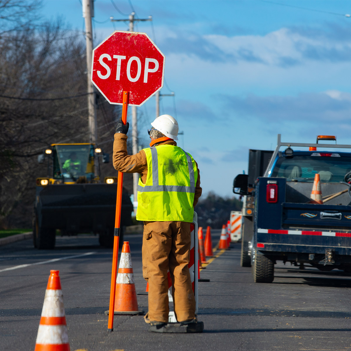 worker holding stop sign for traffic during road milling work